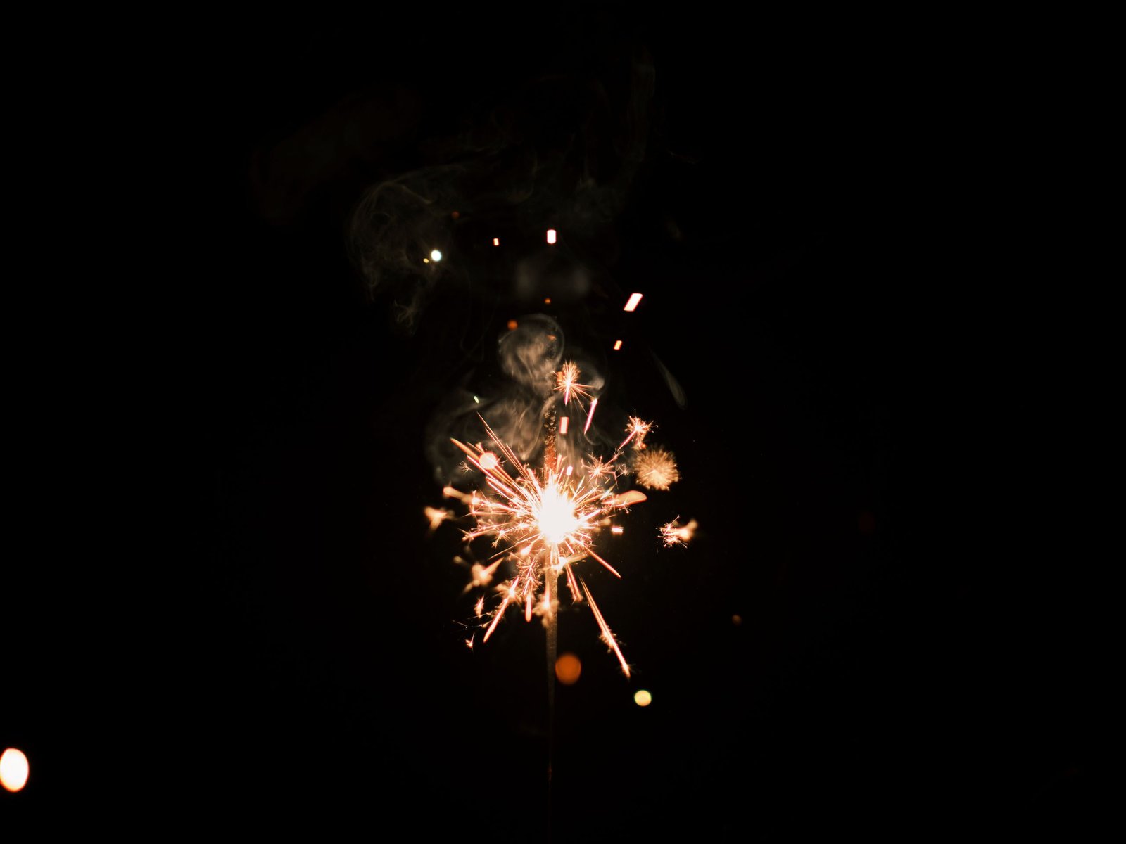 Close-up of a sparkler emitting bright sparks against a dark night sky, creating a mesmerizing effect.